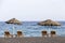 view of Perissa beach on the Greek island of Santorini with sunbeds and umbrellas. Beach is covered with fine black sand, and