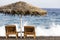 view of Perissa beach on the Greek island of Santorini with sunbeds and umbrellas. Beach is covered with fine black sand, and