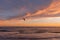 View of a person kitesurfing on the sea during sunset.