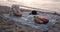 View of Picnic with Nobody and Many Fruits and Bottle of Water on the Sandy Beach of Sea Before Sunrise Dawn, Vacation