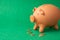 View of piggy bank made of clay, green background with euro coins, horizontal,