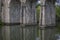 View at the pillars of the old roman bridge over river, in stone, with vegetation around