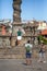 View at the Pillory of Porto city, a ornamented sculpture on plaza ,with tourists, man taking pictures to the girlfriend