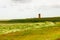 view on Pilsum lighthouse in the landscape of East Frisia with tourists walking around the dike and taking photographs