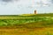 view on Pilsum lighthouse in the landscape of East Frisia with tourists walking around the dike and taking photographs