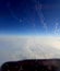 View from the plane on the clouds, the distant land and the wing. Rime on the glass.