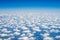 View from the plane`s window: clear blue sky, feathery fluffy clouds. Travel and air transport concept.