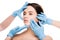 View of plastic surgeons in blue latex gloves touching face of naked woman isolated on white