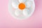 View of plate with flower made of eggs and egg yolk on pink with copy space