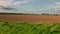 View at plowed field before winter season. Cityscape silhouettes on pale sky with scattered clouds background.