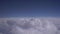 View from the porthole on white dense clouds against a blue sky