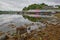 View of Portree harbor with reflections and colorful houses, seen from the seashore, Isle of Skye, Highlands, Scotland, UK