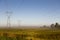 View of power line towers in farmland fields during a beautiful misty late summer golden hour morning