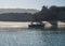 View of Praia das Furnas sand beach with small turquoise wooden boat dock, pier for ferry boats across the river Mira at