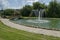 View of public garden with beauty artificial pond, fountain and bridge, town Delchevo among Maleshevo and Osogovo mountains