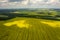 View from the quadrocopter on the field of flowering rapeseed with intricate patterns of clouds floating in the sky