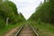 View of railroad track of abandoned old railway in the forest with kilometer post