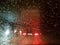 View of the rear of the truck stopped through the windshield with drops of melted snow. Winter night