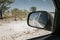 View in rear view mirror while driving through arid dry landscape in Etosha national park Namibia