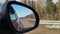 View in the rear view side mirror of a auto, driving a red car