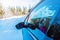 View of the rearview mirror of a moving car on a snowy, winter surface