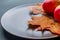 View of red apples and colorful autumn leaves lying on a brown bowl, on a dark gray background. Angled view