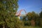 View of the red arch of the cable-stayed bridge through the branches of trees covered with green foliage