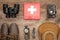 View of red first aid kit, binoculars, photo camera, boots, hat, compass and jackknife on wooden surface