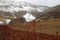 View of red grass and mountain lake under cloudy sky