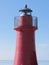 A view of the red harbor lighthouse along the Tuscany coastline in Castiglione della Pescaia, Italy