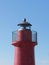 A view of the red harbor lighthouse along the Tuscany coastline in Castiglione della Pescaia, Italy