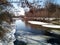 View of the river opened from the ice with forested banks from under the branches of Acer negundo. Horizontal photo