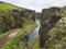 View on river stream and green moss covered cliffs and hills in