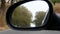 View of the road in the rear view mirror of a traveling car.