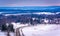 View of road through snow-covered fields and distant mountains,