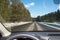 View of the road through the windshield. Snow on the sidelines. Wet asphalt road. Blue sky with clouds. Point of view of the