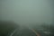 View of roadway and fence full of white fog while driving through local road on rainy and bad weather day on mount Aso area