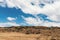 View of rocky land with white clouds and blue sky in the background. Mountainous nature background