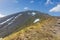 A view of a rocky Scottish mountain Ben Vorlich summit with rocky and grassy slope under a majestic blue sky and white clouds