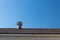 View of roof and old style spinning attic ventilator against a blue sky