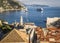 View of the roofs of houses and the bay with ships in the city of Dubrovnik in sunny summer