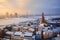 View of the roofs of the old city and the tower of the Dome Cathedral against background of an ice-covered river.