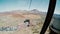 View from a ropeway cabin to mountains and station of departure. Cablecar moves up to the top of volcano.