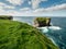 View on rough small island in the ocean from a cliff, Ireland, Kilkee area. Warm sunny day, blue cloudy sky. Travel, tourism and