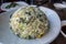 View of a round scoop of vegetable and mushroom fried rice on a small, white plate inside an Asian restaurant