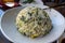 View of a round scoop of vegetable and mushroom fried rice on a small, white plate inside an Asian restaurant