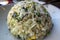 View of a round scoop of vegetable and mushroom fried rice on a small, white plate inside an Asian restaurant