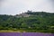 View on rows of blossoming purple lavender, green fiels and Lacoste village in Luberon, Provence, France in July