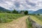 View of a rustic stone cottage in midst of a vineyard with a trail running along a rock wall in the foreground and a great view of