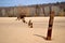 View of the rusty remains of an iron fence on the sandy bank of the river.